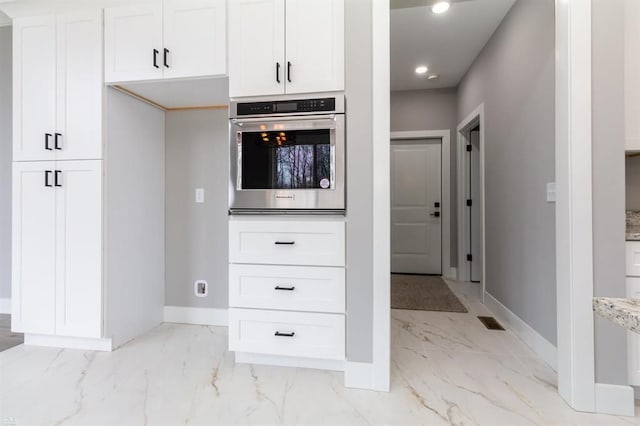 kitchen with white cabinets, oven, and light stone counters