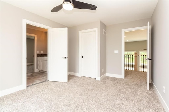 unfurnished bedroom with ensuite bathroom, ceiling fan, and light colored carpet