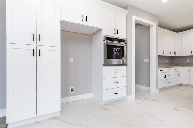 kitchen with white cabinetry, oven, and light stone counters