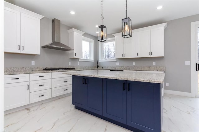 kitchen with wall chimney exhaust hood, white cabinetry, and decorative light fixtures