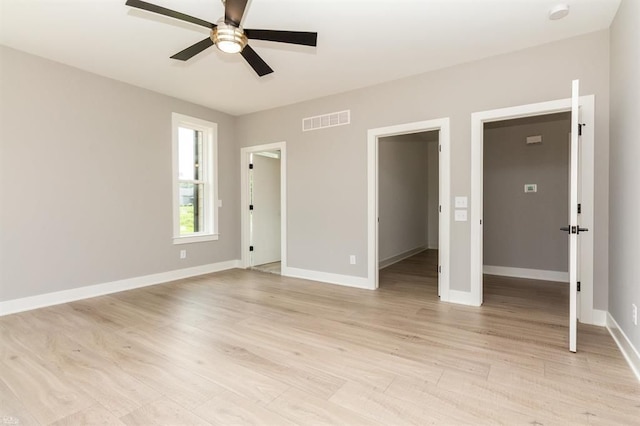 unfurnished bedroom with ceiling fan, light hardwood / wood-style floors, a spacious closet, and a closet