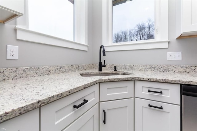 kitchen featuring dishwasher, light stone countertops, sink, and white cabinets