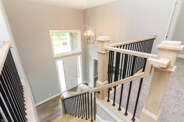 staircase featuring a chandelier, a towering ceiling, and hardwood / wood-style flooring