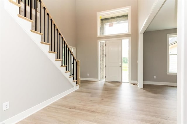 entryway featuring light hardwood / wood-style flooring and a towering ceiling