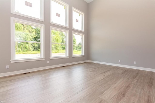 empty room with light hardwood / wood-style floors and a towering ceiling