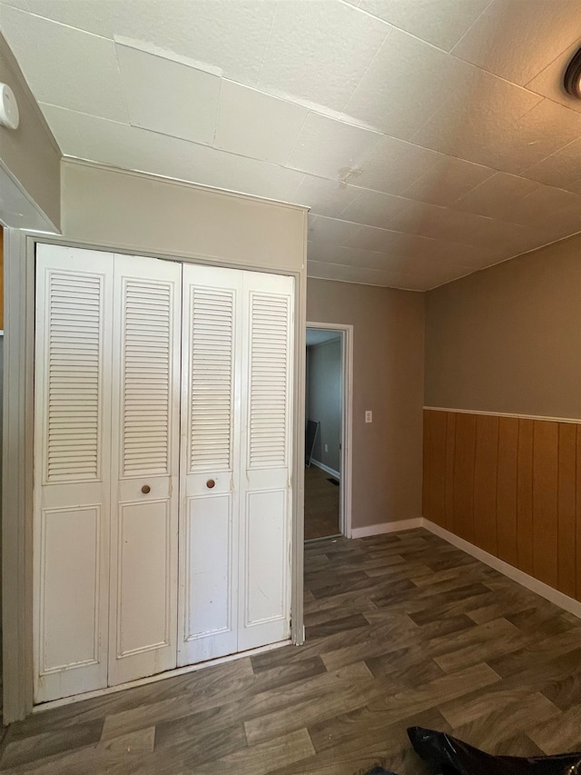 hallway featuring wooden walls and dark wood-type flooring