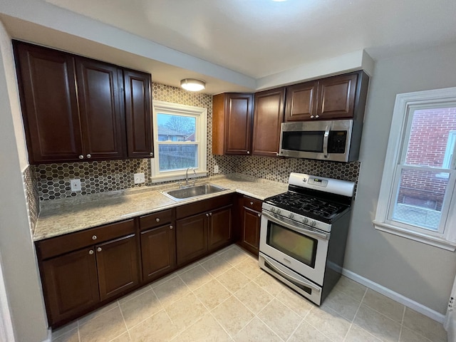 kitchen with dark brown cabinets, stainless steel appliances, tasteful backsplash, and sink