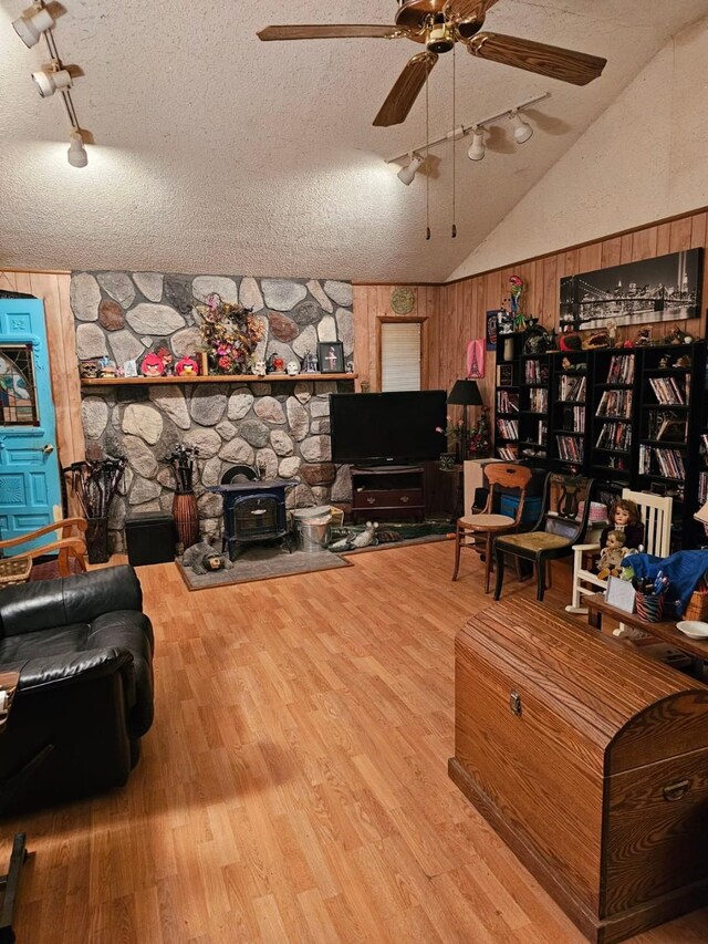 227 Joliet Ave, Houghton Lake, MI 48629 - living area with wood finished floors, a wood stove, ceiling fan, a textured ceiling, and wooden walls