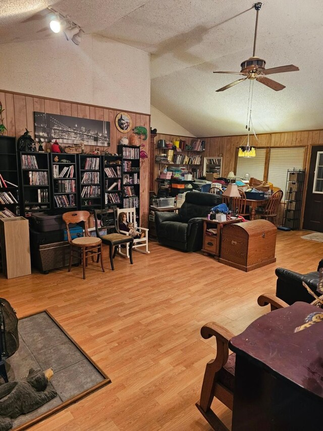 227 Joliet Ave, Houghton Lake, MI 48629 - living area with a ceiling fan, wood finished floors, wood walls, vaulted ceiling, and a textured ceiling