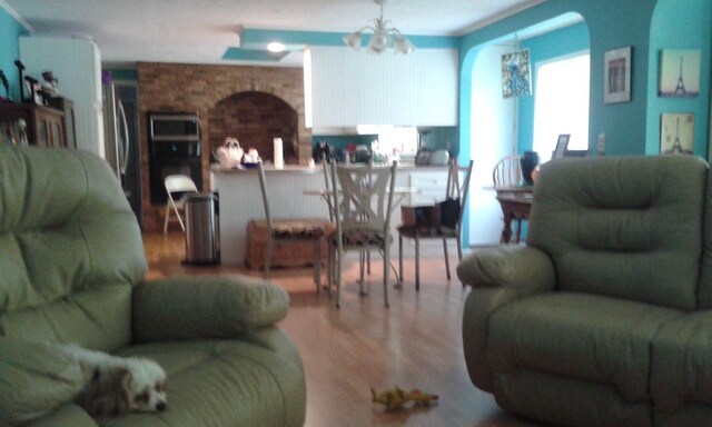 227 Joliet Ave, Houghton Lake, MI 48629 - living area featuring wood finished floors, a chandelier, and arched walkways