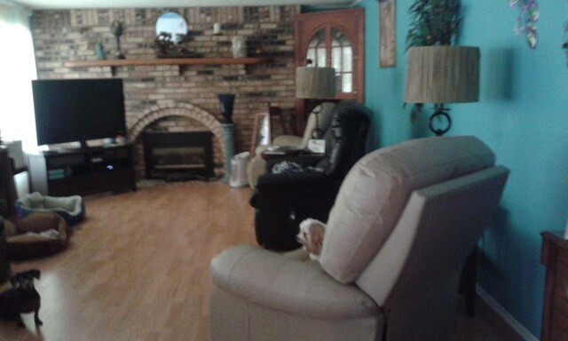227 Joliet Ave, Houghton Lake, MI 48629 - living room featuring wood finished floors and a brick fireplace