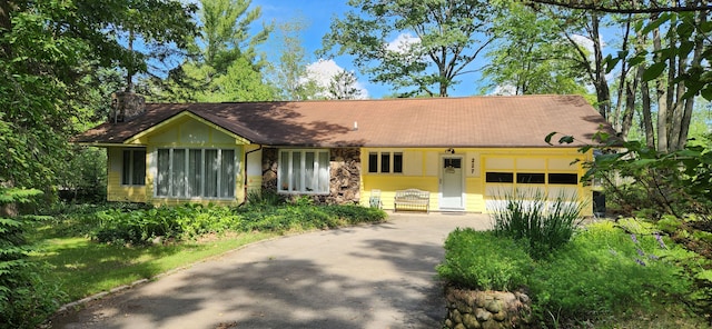 227 Joliet Ave, Houghton Lake, MI 48629 - view of front of home featuring driveway, a garage, a chimney, and stone siding