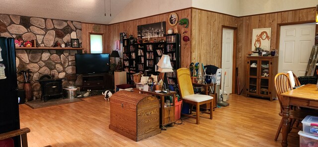 227 Joliet Ave, Houghton Lake, MI 48629 - living room with vaulted ceiling, a wood stove, wood walls, and wood finished floors