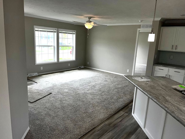 interior space with ornamental molding, ceiling fan, dark wood-type flooring, white cabinets, and hanging light fixtures