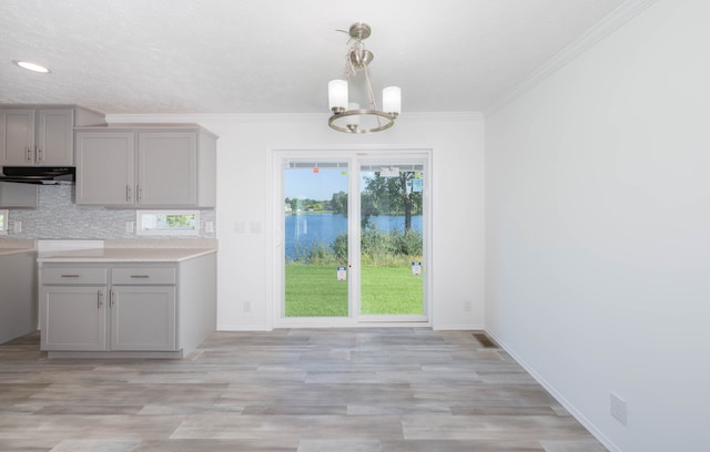 kitchen featuring ventilation hood, gray cabinets, crown molding, and an inviting chandelier