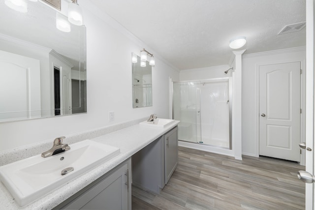 bathroom featuring ornamental molding, vanity, a textured ceiling, a shower with door, and hardwood / wood-style flooring