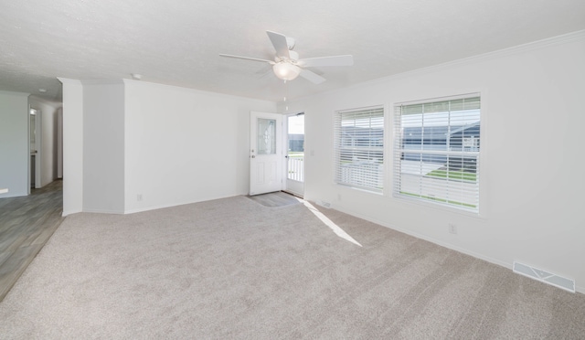 empty room with ceiling fan, light colored carpet, and crown molding