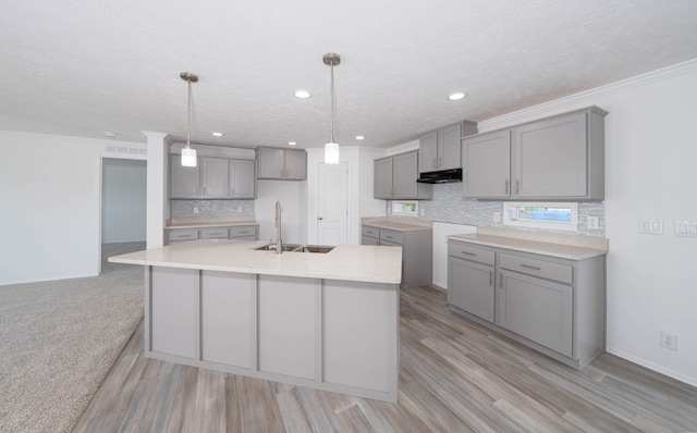 kitchen with pendant lighting, light hardwood / wood-style floors, ornamental molding, and gray cabinetry