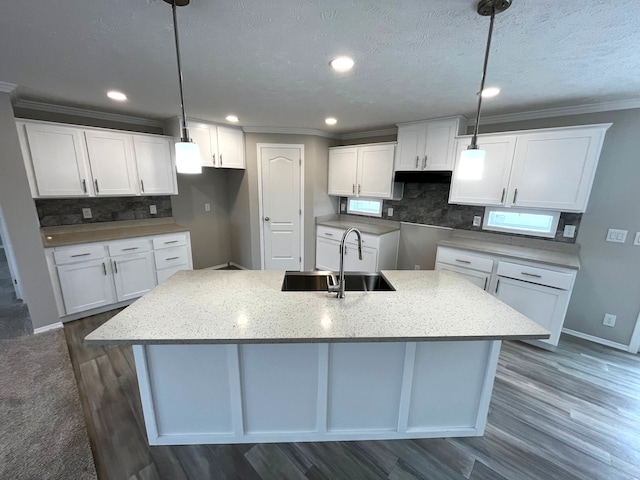 kitchen with pendant lighting, a center island with sink, sink, dark hardwood / wood-style floors, and white cabinetry