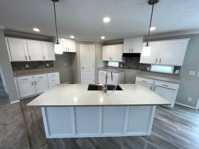 2765 Naples Ct, Lapeer, MI 48446 - kitchen featuring a sink, a kitchen island with sink, white cabinets, tasteful backsplash, and crown molding
