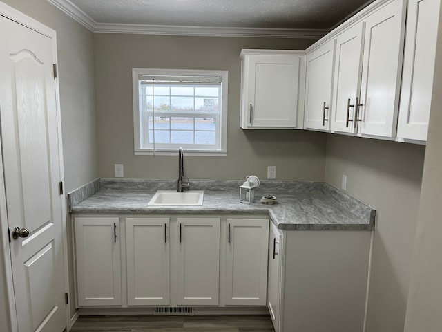 kitchen featuring white cabinets, crown molding, and sink