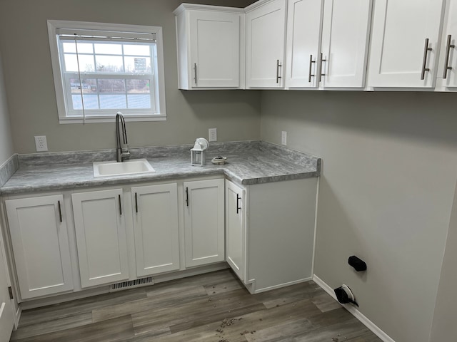 laundry area with cabinets, sink, and dark wood-type flooring