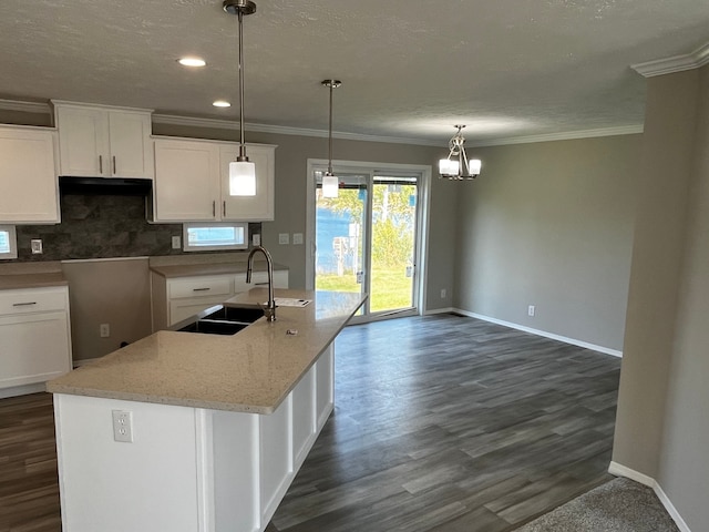 kitchen with dark hardwood / wood-style flooring, sink, decorative light fixtures, a center island with sink, and white cabinets