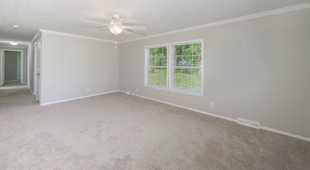 empty room featuring a textured ceiling, ceiling fan, crown molding, and light carpet