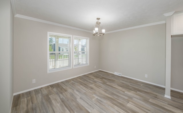 empty room featuring a chandelier, crown molding, and light hardwood / wood-style floors