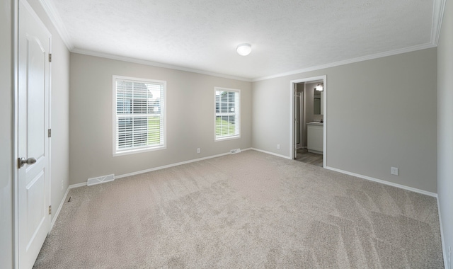 unfurnished bedroom featuring a textured ceiling, carpet floors, ensuite bath, and ornamental molding