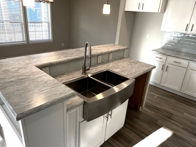 kitchen featuring dark wood-type flooring, white cabinets, pendant lighting, and sink