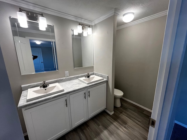 bathroom featuring hardwood / wood-style floors, vanity, a textured ceiling, and ornamental molding