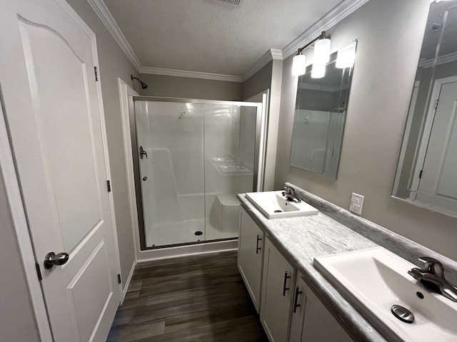 bathroom with hardwood / wood-style flooring, crown molding, a shower with door, and a textured ceiling