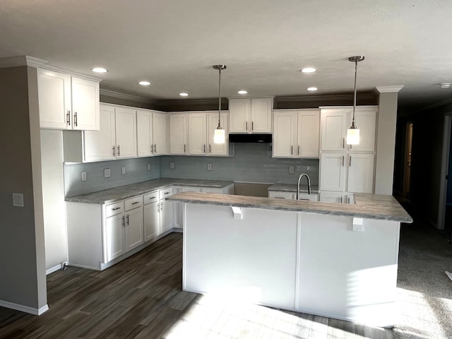 kitchen with white cabinets, decorative light fixtures, and a center island with sink