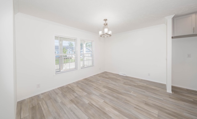 spare room featuring crown molding, light hardwood / wood-style flooring, and a chandelier