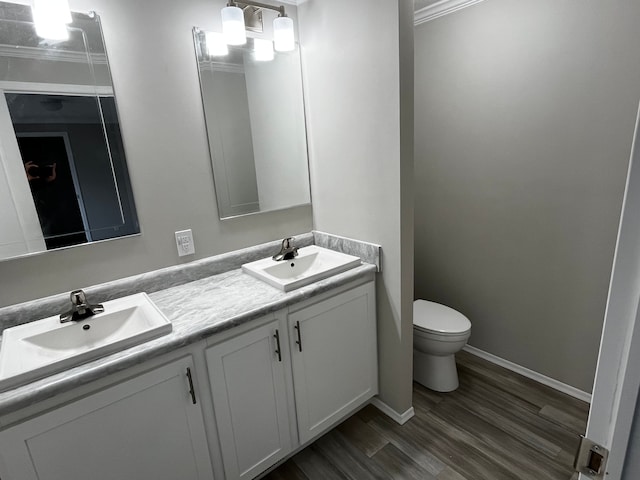 bathroom featuring crown molding, vanity, wood-type flooring, and toilet