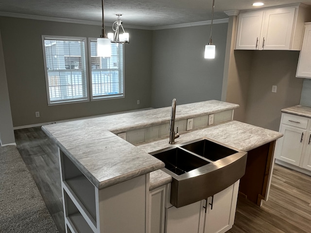 kitchen featuring pendant lighting, white cabinets, dark hardwood / wood-style flooring, and an island with sink