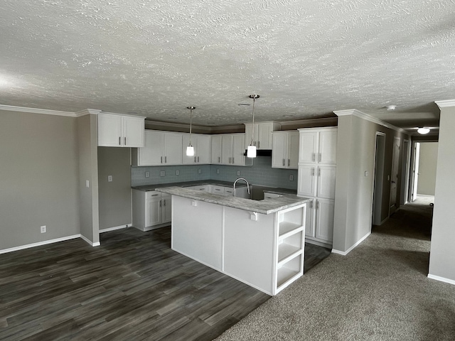 kitchen featuring a kitchen island with sink, dark wood-type flooring, decorative backsplash, decorative light fixtures, and white cabinetry