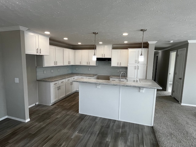 kitchen featuring white cabinets, decorative light fixtures, and a center island with sink