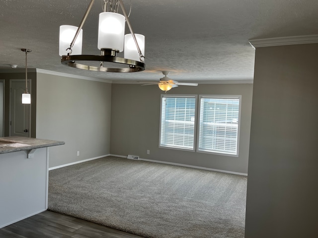 unfurnished dining area with ceiling fan, ornamental molding, a textured ceiling, and dark wood-type flooring