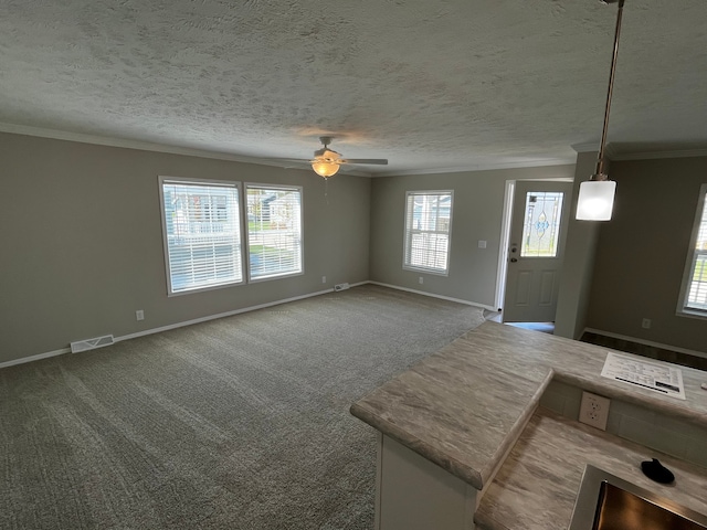 carpeted foyer featuring ceiling fan, ornamental molding, and a textured ceiling