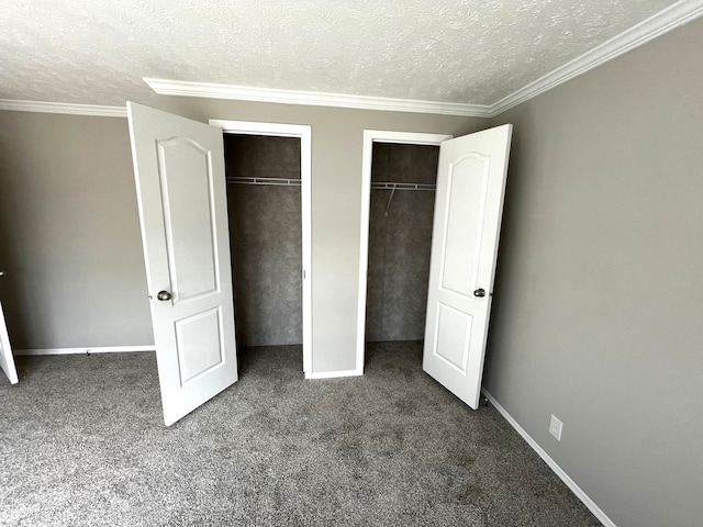 unfurnished bedroom with multiple closets, dark carpet, a textured ceiling, and ornamental molding