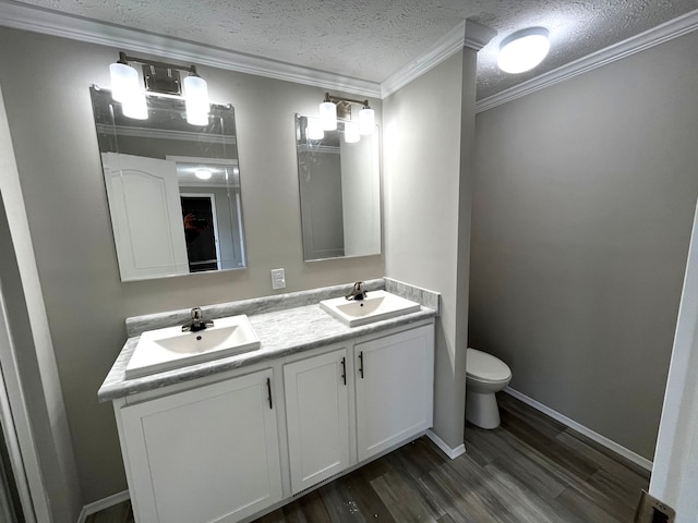 bathroom with hardwood / wood-style floors, vanity, crown molding, toilet, and a textured ceiling