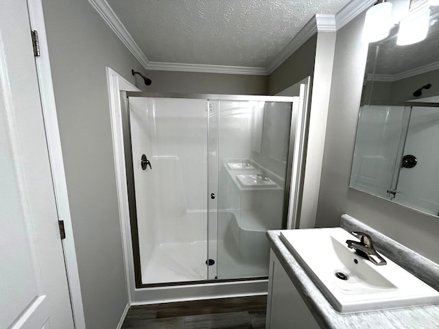 bathroom with walk in shower, crown molding, a textured ceiling, vanity, and hardwood / wood-style flooring