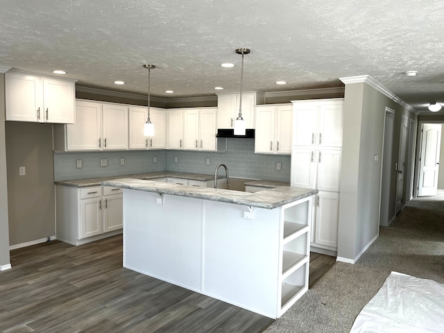 kitchen with pendant lighting, white cabinetry, and an island with sink