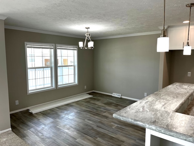 unfurnished dining area featuring a textured ceiling, a notable chandelier, dark hardwood / wood-style floors, and ornamental molding