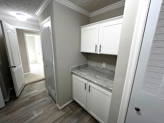 bar featuring a textured ceiling, white cabinetry, crown molding, and dark hardwood / wood-style floors