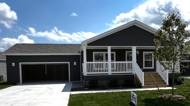 view of front of home with a porch, a garage, a front yard, and central AC