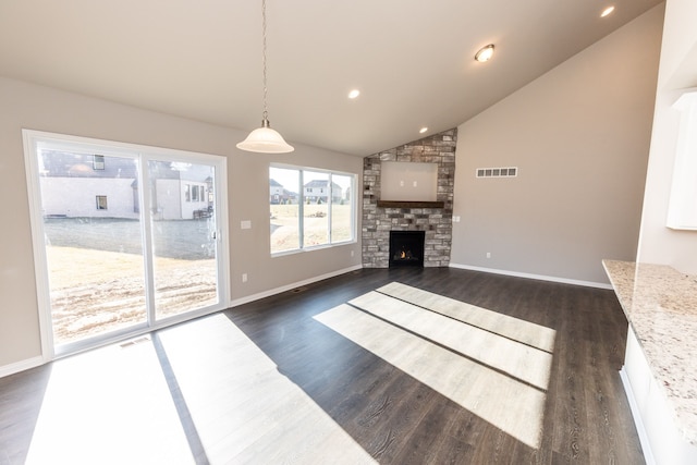 unfurnished living room with dark hardwood / wood-style floors, a stone fireplace, and high vaulted ceiling