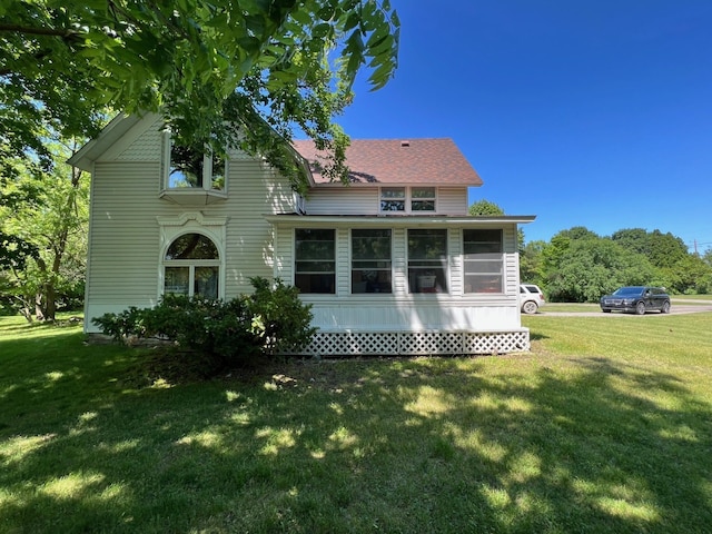 rear view of property with a sunroom and a lawn